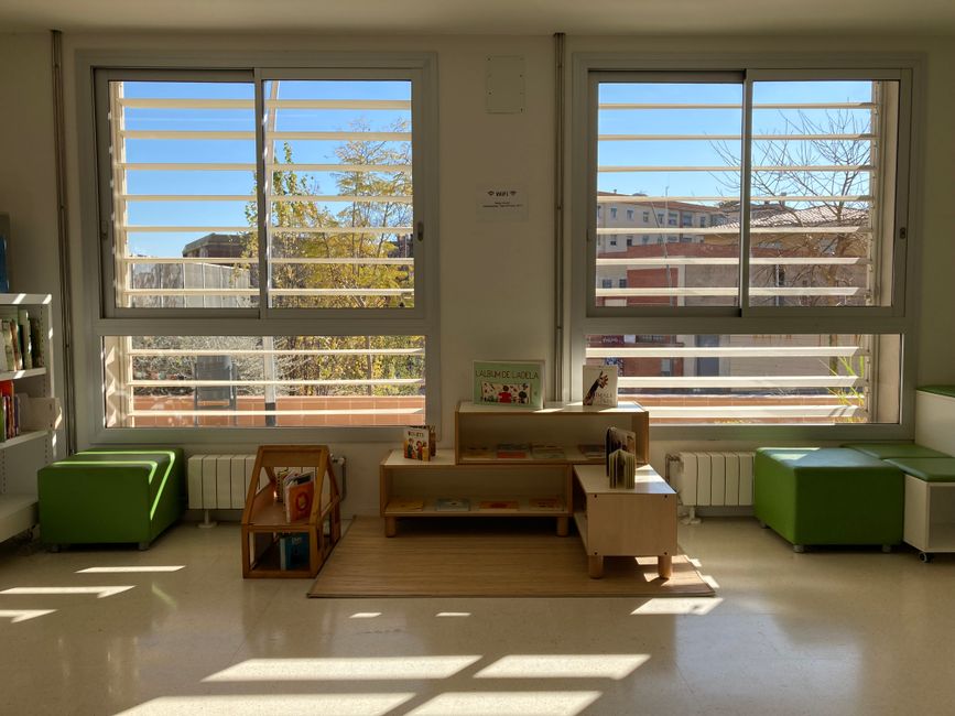Sunny kindergarten reading area with bookshelves and seating in Barcelona, Spain.