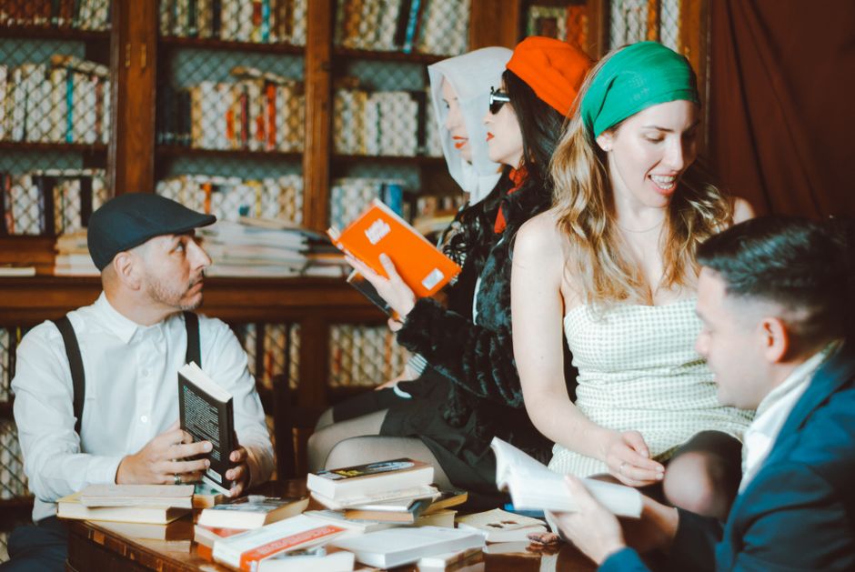 Group of people reading books in a vintage-style library. Cozy and intellectual atmosphere.